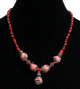 Collier ethnique artisanal imitation pierres corail rose agrementees de perles rouges et noires et d'armatures en metal