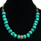 Collier ethnique artisanal imitation boules difformes turquoises separees de perles noires, compose d'autres perles vertes et en bois avec une boule en metal au milieu